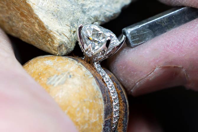 custom diamond ring being finished on a stone surface with a tool