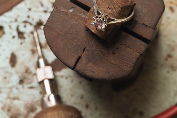 Gold ring with a diamond on a wooden anvil with tools in the background